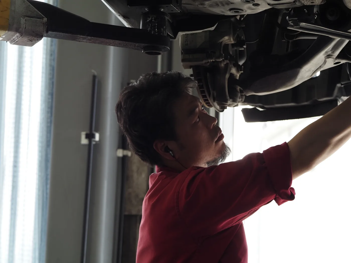 リフト下で車両を点検するメカニック