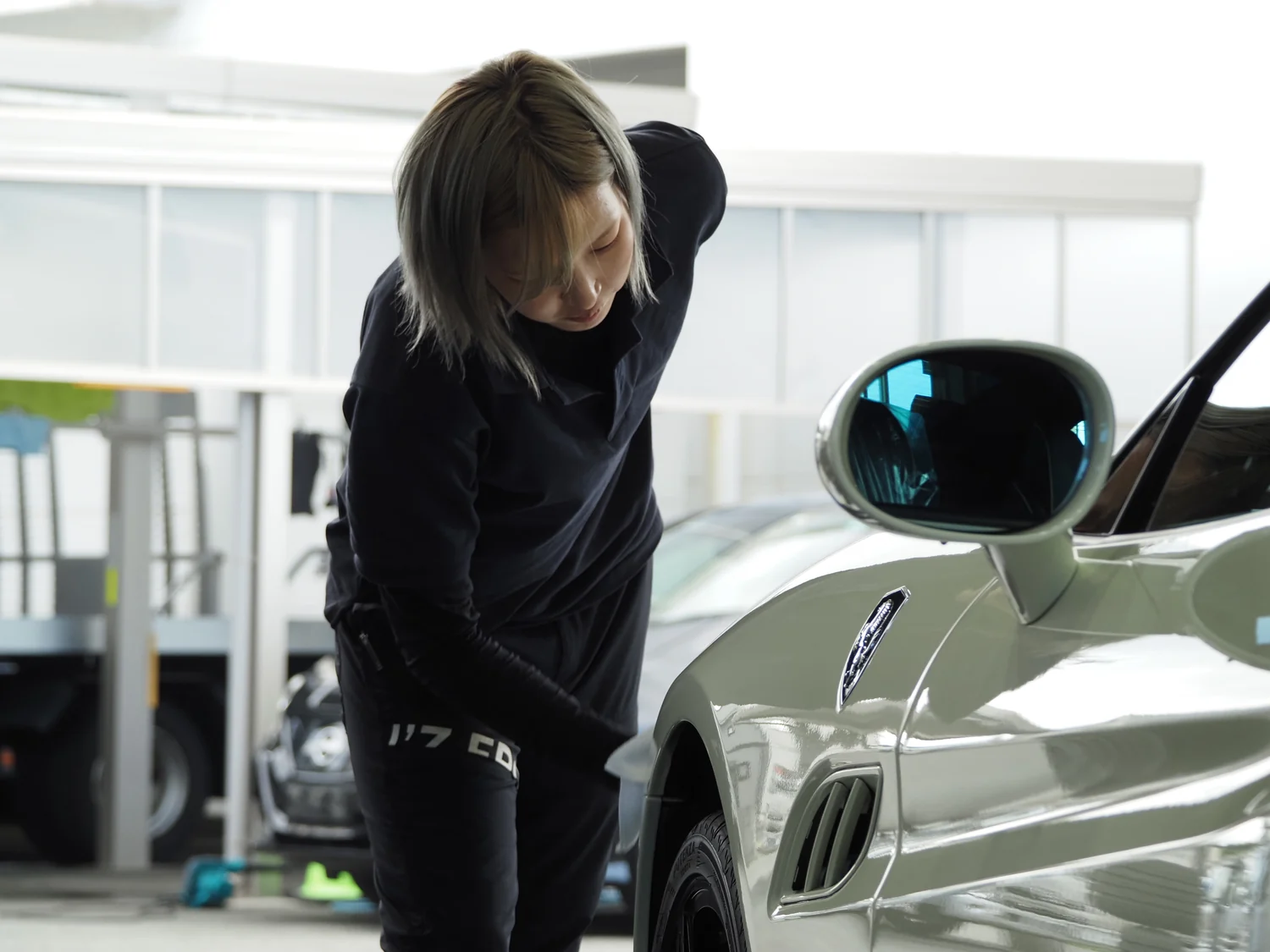 白い車両の外装状態を確認するスタッフ